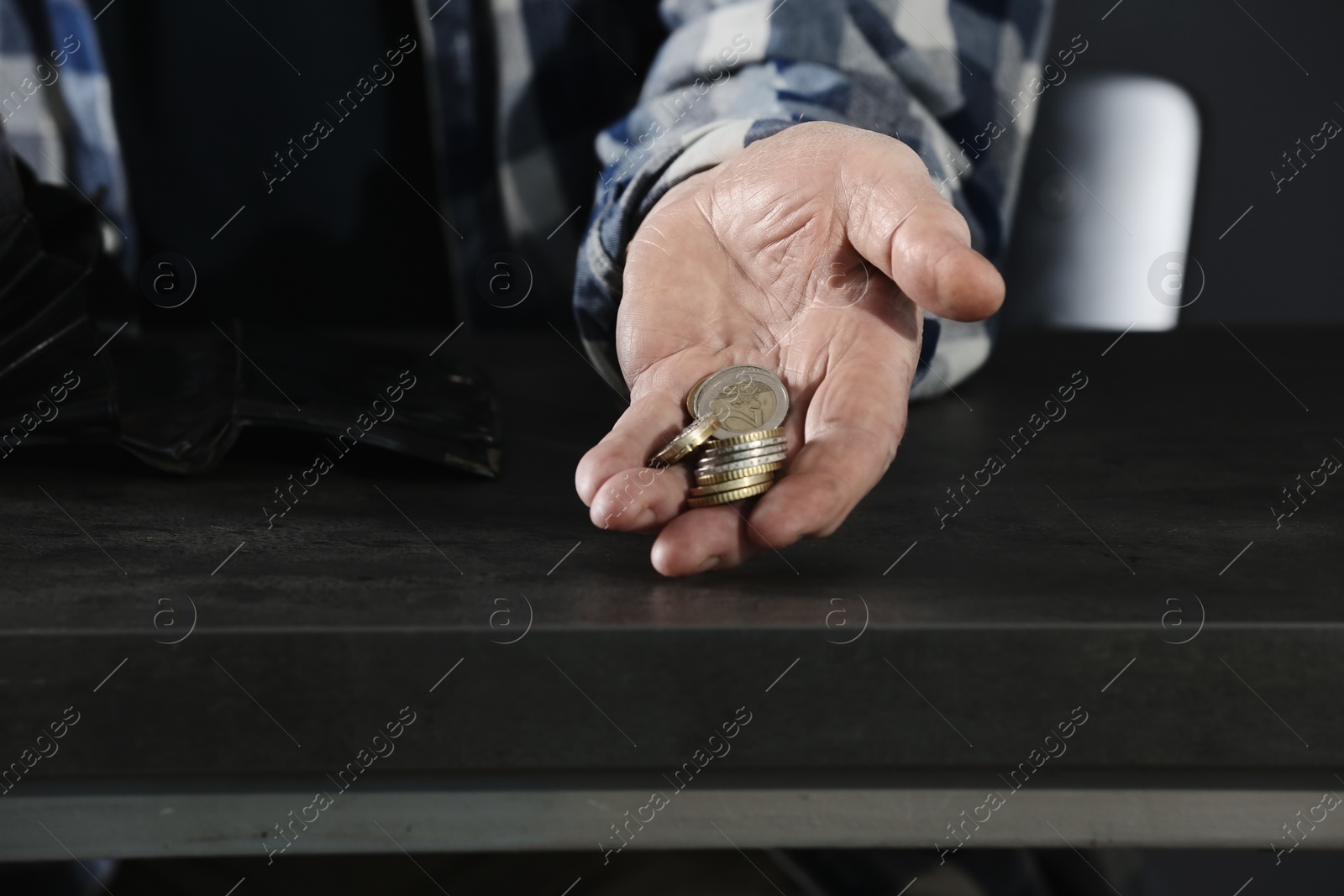 Photo of Poor elderly man holding coins in hand at table, closeup