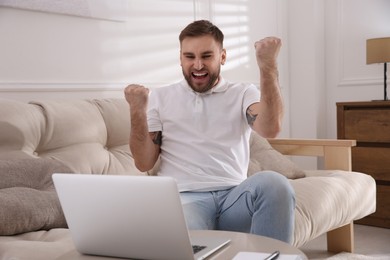 Photo of Emotional man participating in online auction using laptop at home