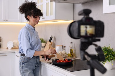 Photo of Smiling food blogger cooking while recording video in kitchen