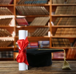 Image of Graduation hat and diploma on wooden table in library