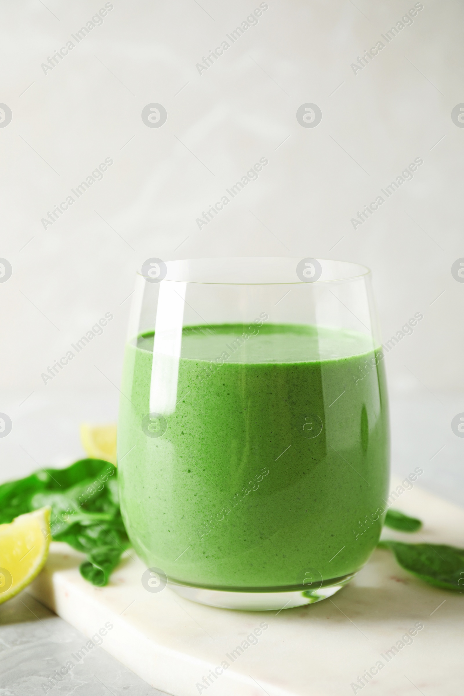 Photo of Glass of healthy green smoothie with fresh spinach on light table