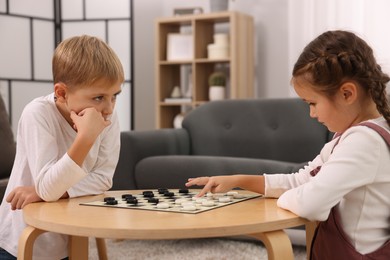 Children playing checkers at coffee table in room