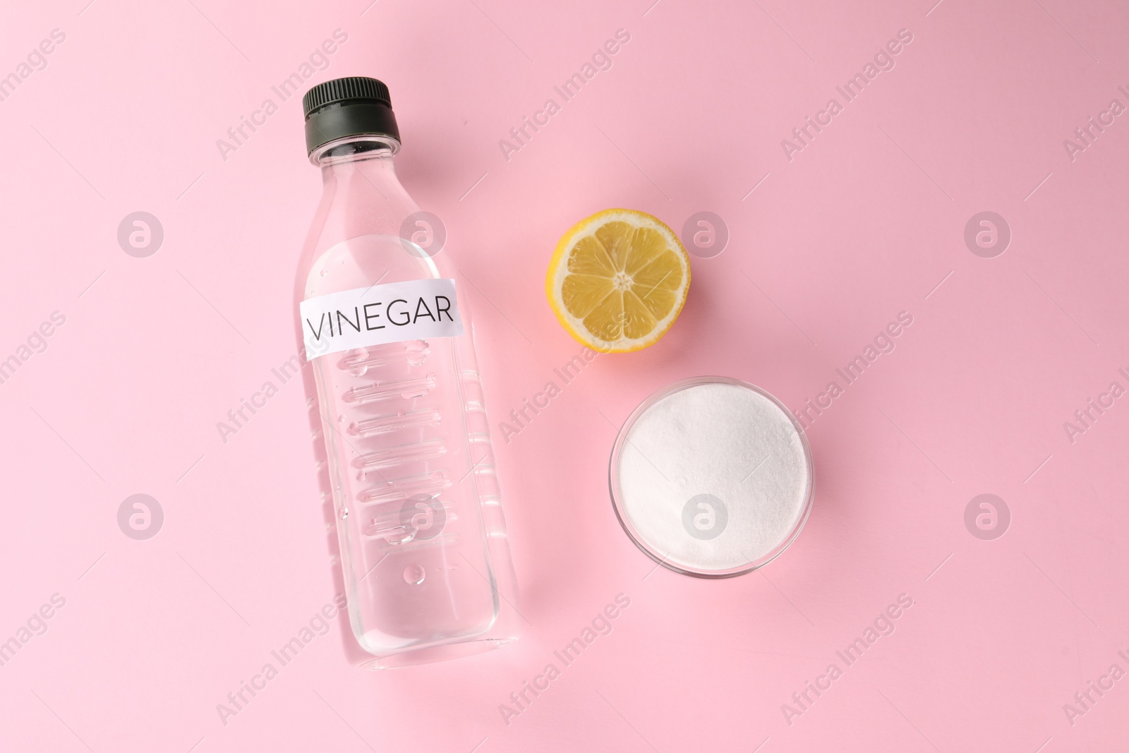 Photo of Eco friendly natural cleaners. Vinegar in bottle, cut lemon and bowl of soda on pink background, flat lay