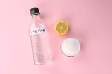 Eco friendly natural cleaners. Vinegar in bottle, cut lemon and bowl of soda on pink background, flat lay