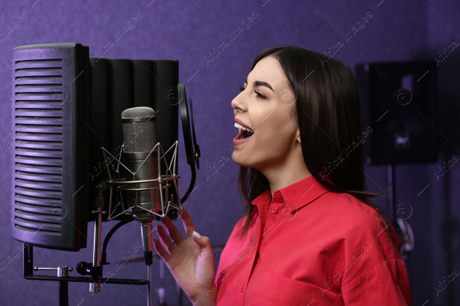 Photo of Young singer with microphone recording song in studio