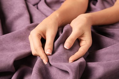Photo of Woman touching soft purple fabric, closeup view