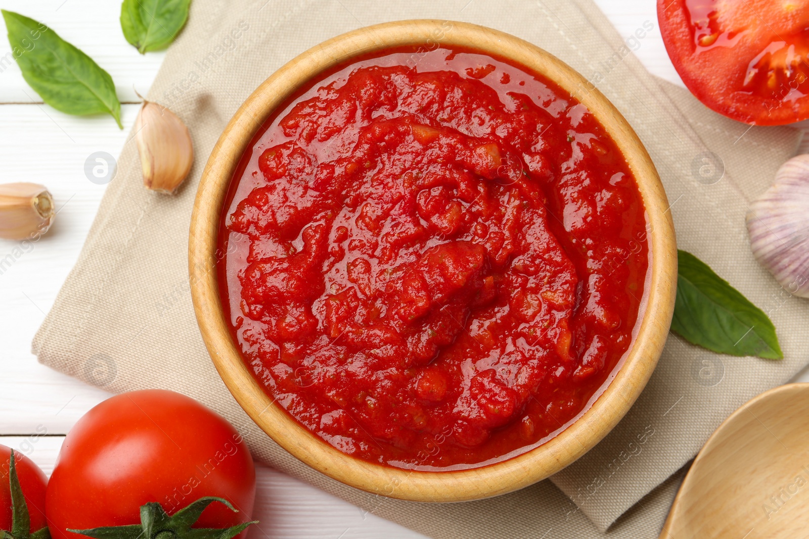 Homemade tomato sauce in bowl and fresh ingredients on white wooden table, flat lay Photo of Homemade tomato sauce in bowl and fresh ingredients on white wooden table, flat lay