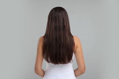 Photo of Woman with damaged messy hair on grey background, back view