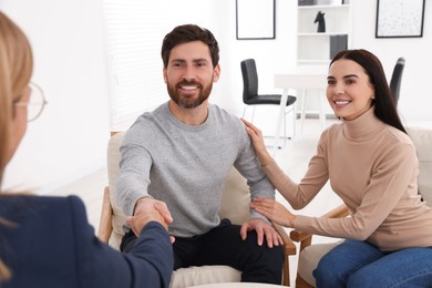 Photo of Real estate agent shaking hands with client at table in office