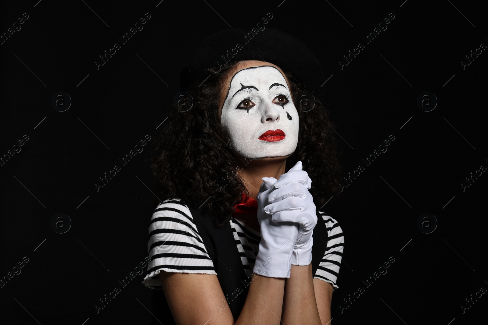 Photo of Young woman in mime costume posing on black background