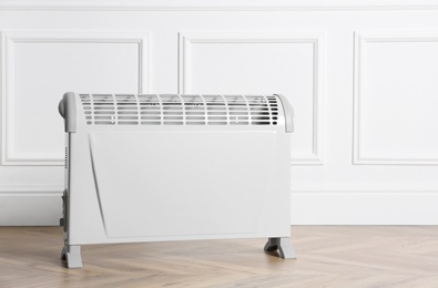 Modern electric convection heater on floor in room, space for text