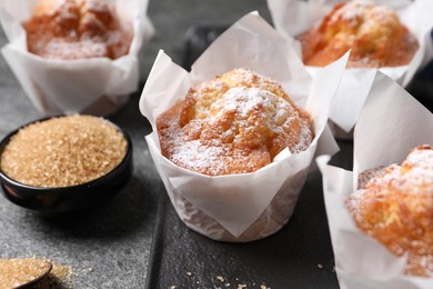 Photo of Delicious muffins with powdered sugar on grey table, closeup