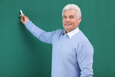 Photo of Portrait of senior teacher with chalk at green board