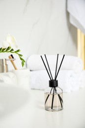 Photo of Aromatic reed air freshener on white countertop in bathroom