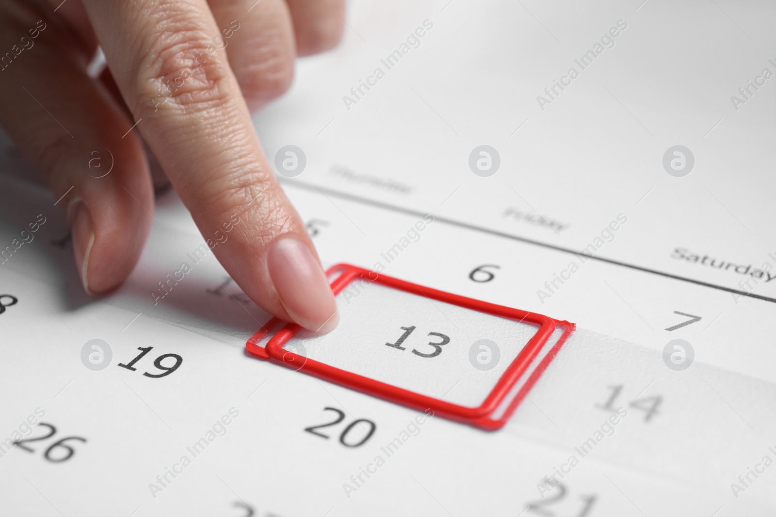 Photo of Woman putting reminder on Friday 13, closeup. Bad luck superstition