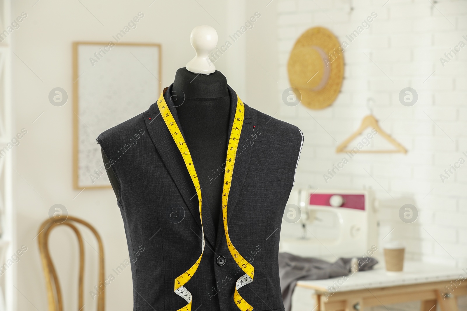 Photo of Mannequin with unfinished jacket and measuring tape in tailor shop