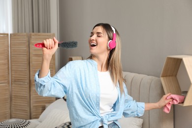 Woman in headphones with hairbrush singing at home
