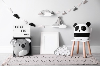 Photo of Empty photo frame and cute toys near wall in baby room. Interior design