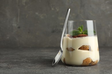 Delicious tiramisu with mint in glass on grey table. Space for text