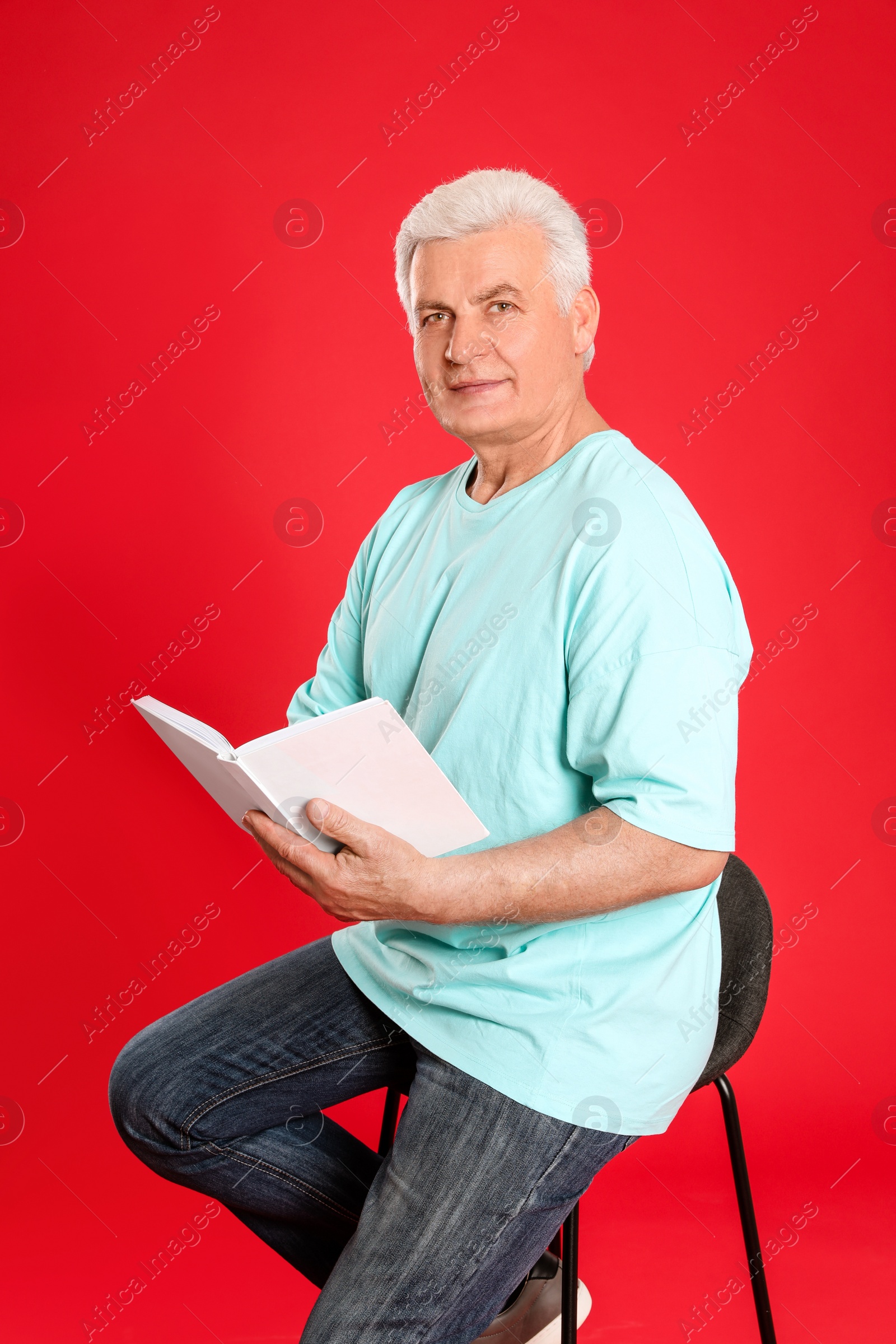 Photo of Senior man reading book on color background