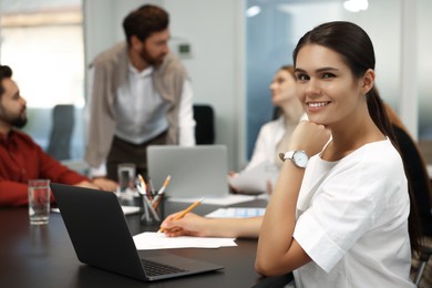 Team of employees working together in office. Happy woman at table indoors