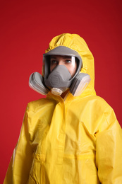 Photo of Woman wearing chemical protective suit on red background. Virus research