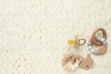 Photo of Cute baby pacifier and toys on light knitted fabric, flat lay. Space for text
