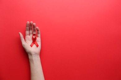 Photo of Woman holding red awareness ribbon on color background, top view with space for text. World AIDS disease day