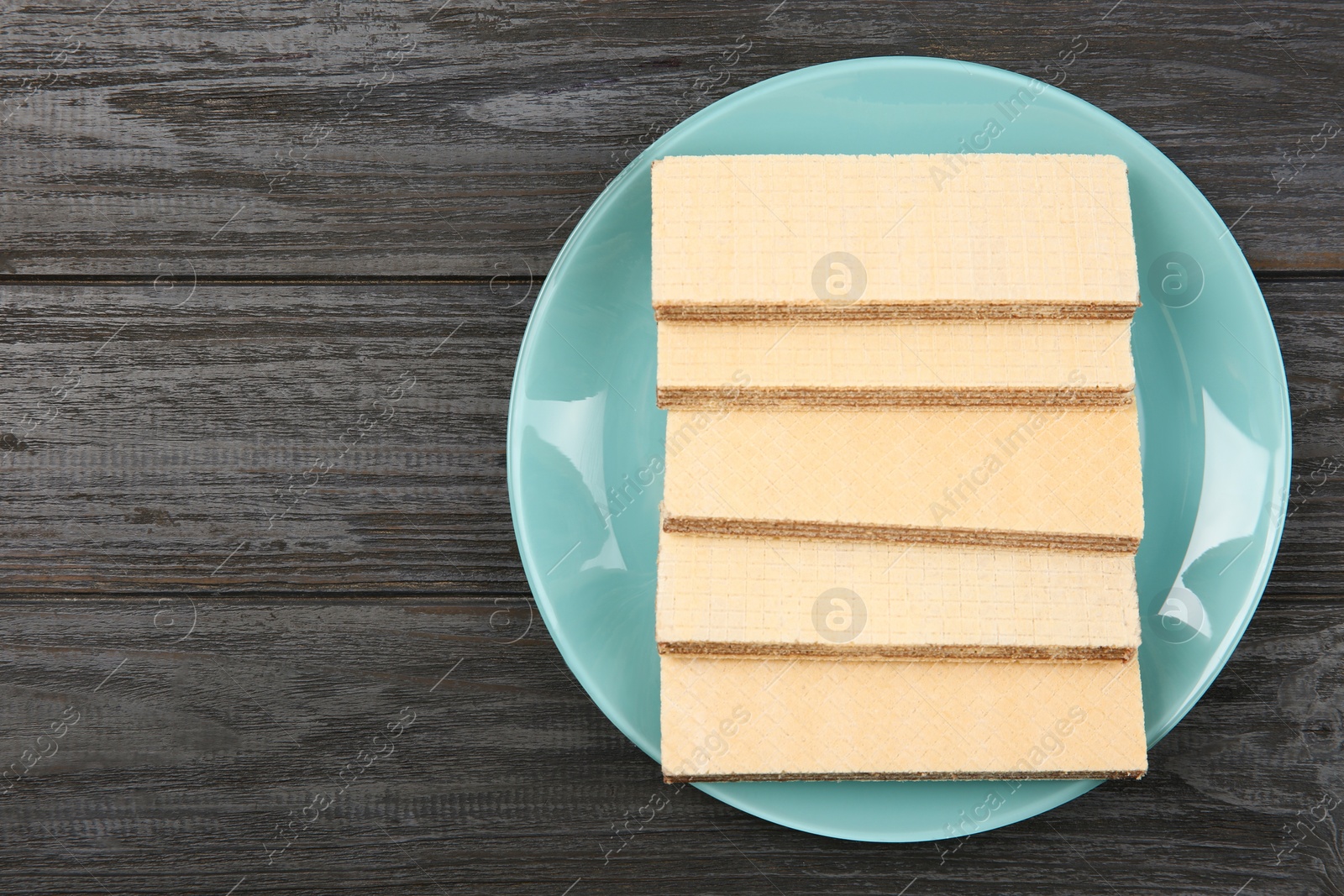 Photo of Plate with delicious crispy wafers on wooden table, top view. Space for text