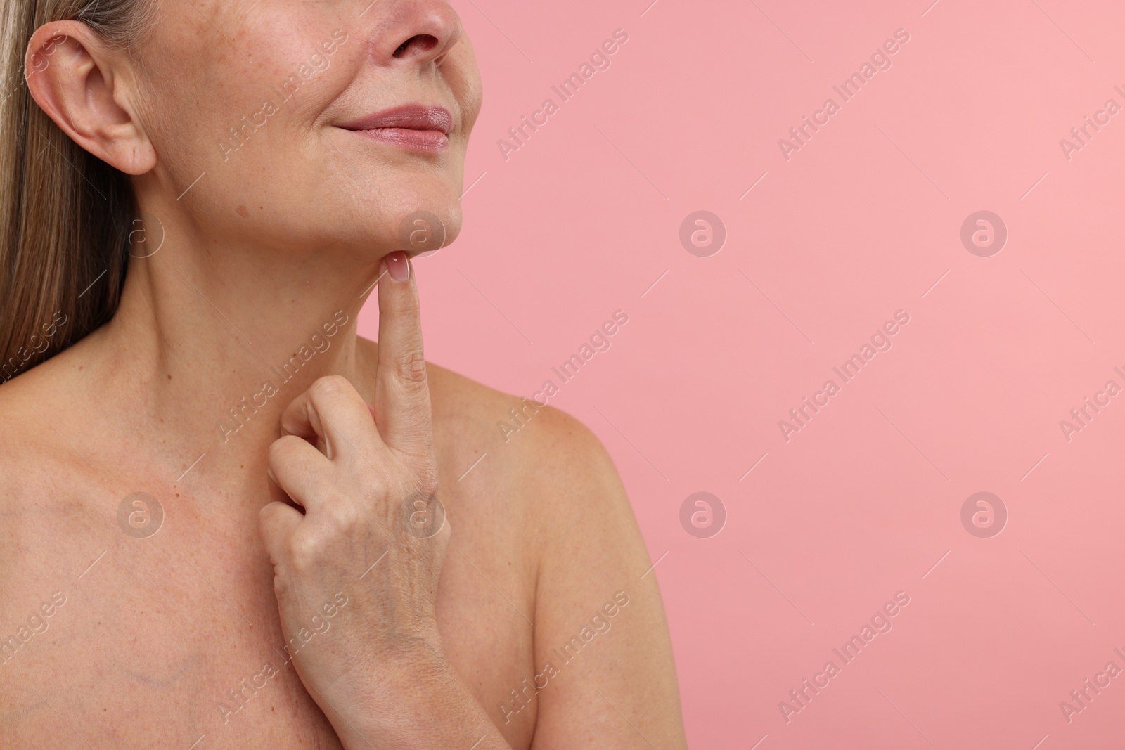 Photo of Mature woman with healthy skin on pink background, closeup. Space for text