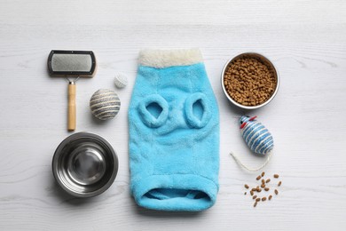 Photo of Flat lay composition with clothes, food and accessories for cat on white wooden table