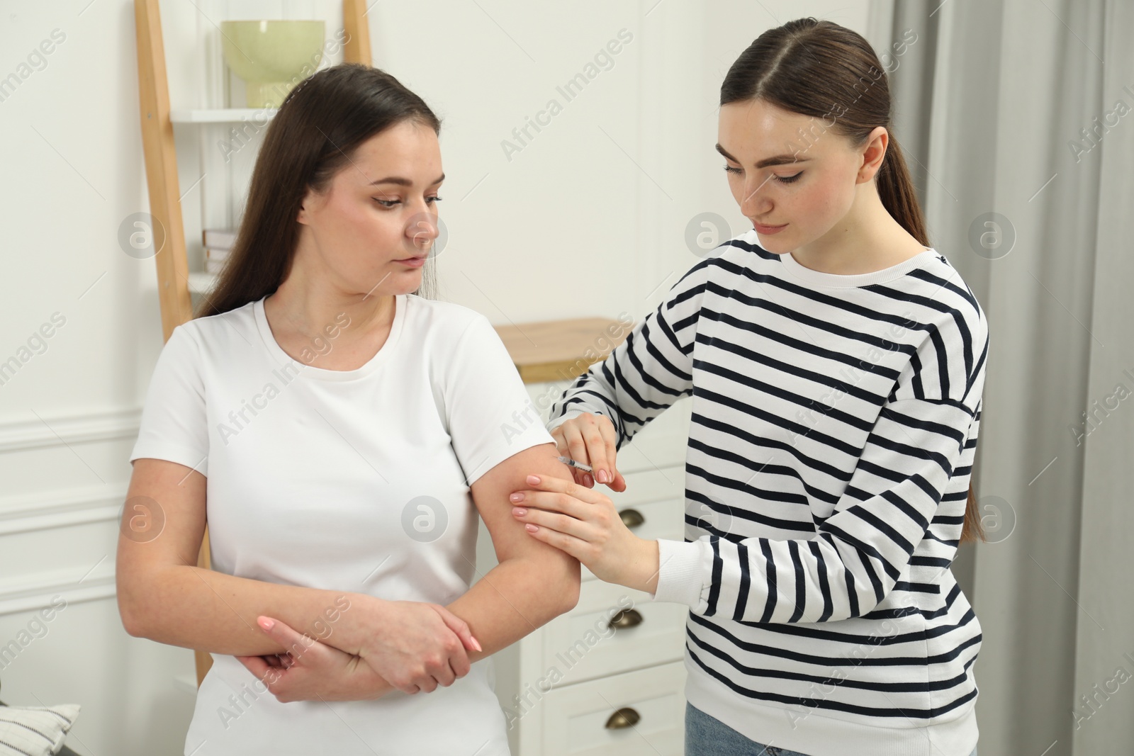 Photo of Woman giving insulin injection to her diabetic friend at home