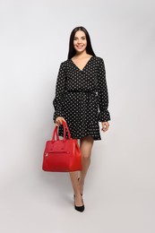 Young woman with stylish bag on white background,