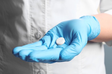 Photo of Doctor in medical glove holding pill, closeup view