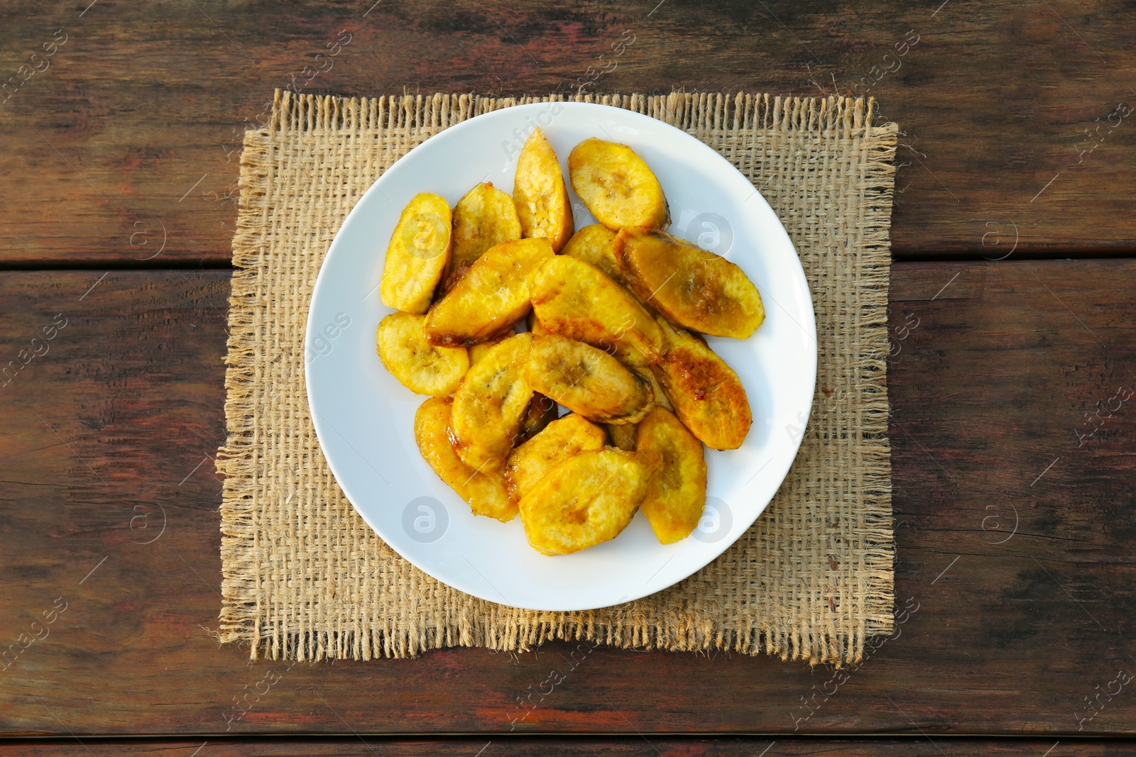 Photo of Tasty deep fried banana slices on wooden table, top view