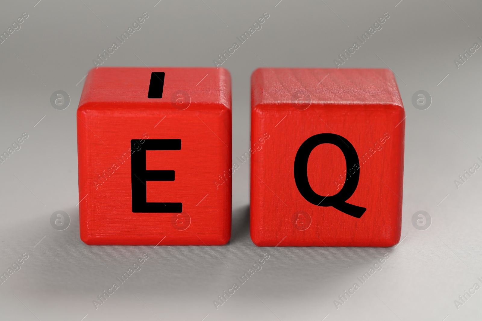 Photo of Red cubes with abbreviation IQ on light grey background