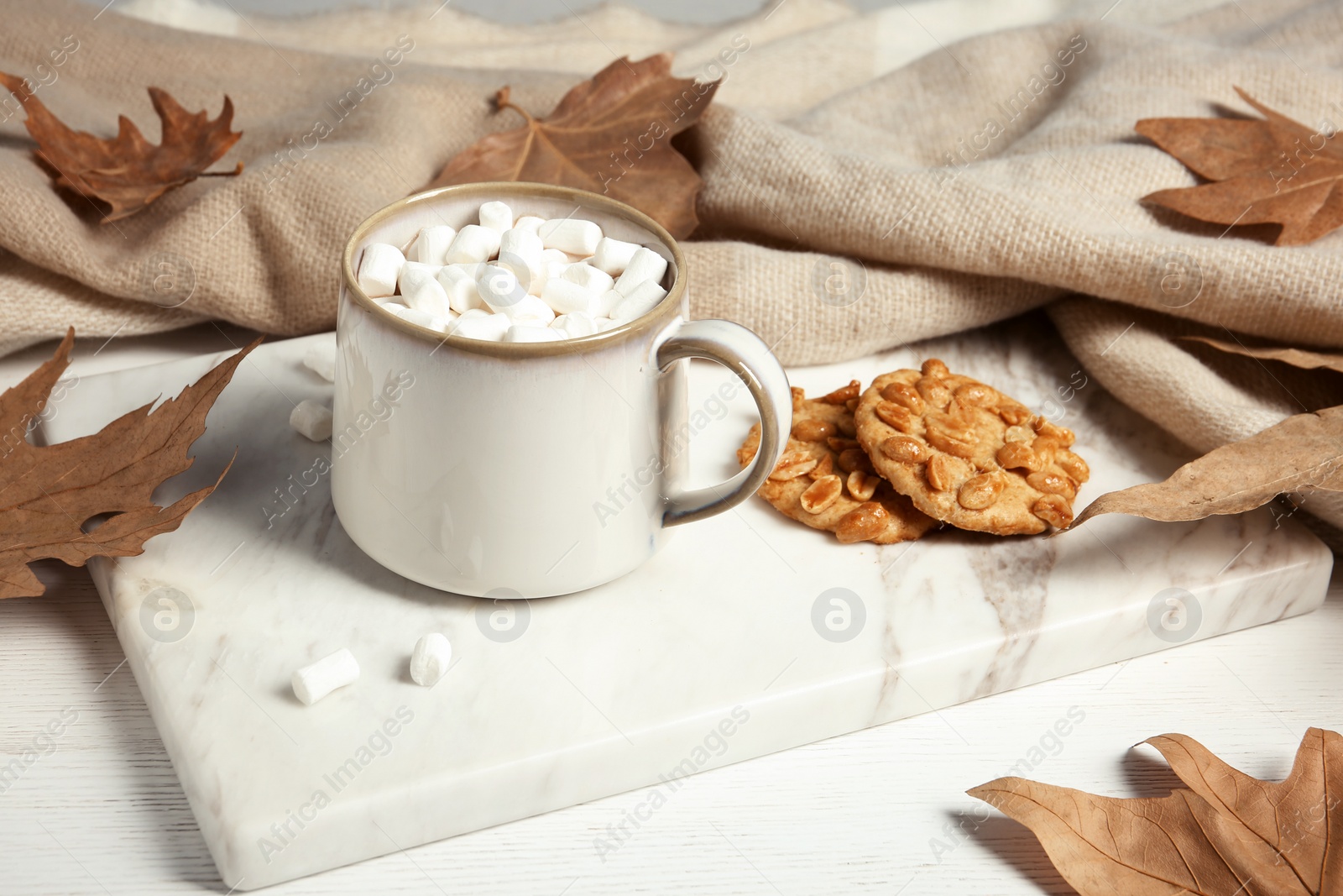 Photo of Cup of hot cozy drink, tasty cookies and  autumn leaves on table