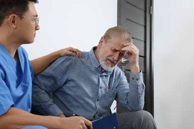 Photo of Doctor with clipboard consulting senior patient in clinic