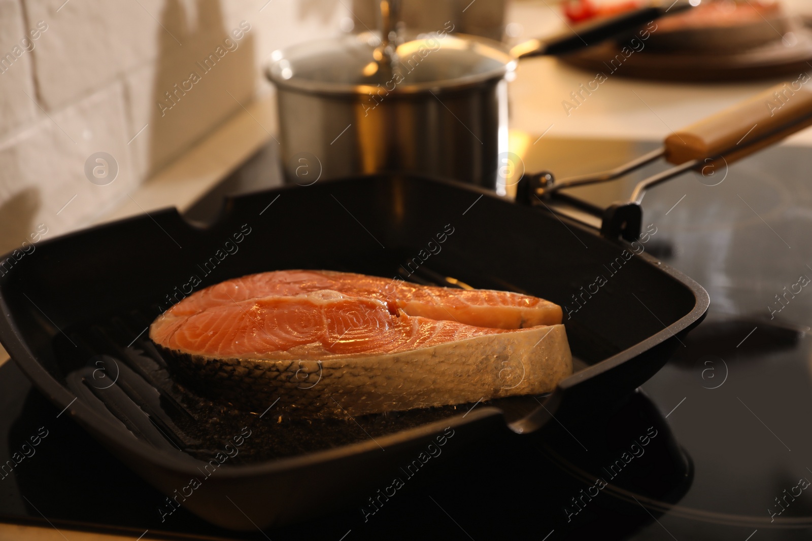 Photo of Frying pan with fresh salmon steak on stove