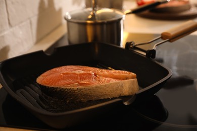 Photo of Frying pan with fresh salmon steak on stove