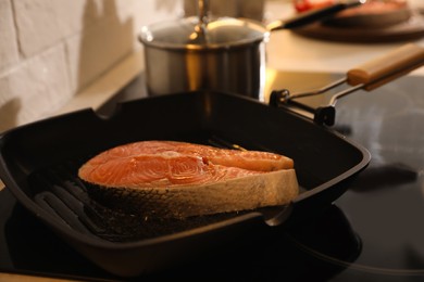 Frying pan with fresh salmon steak on stove