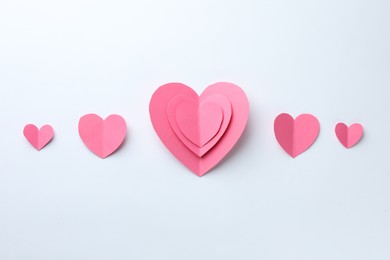 Photo of Pink paper hearts on white background, flat lay