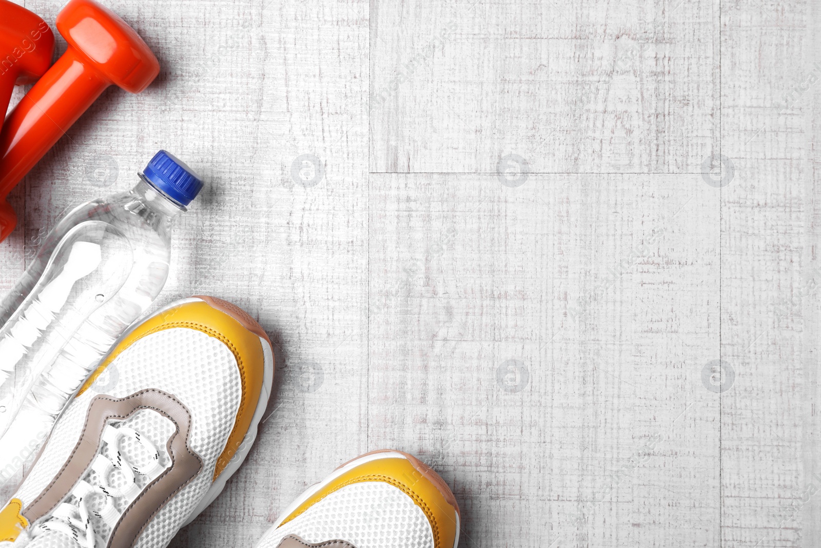Photo of Flat lay composition with dumbbells, sneakers and space for text on wooden background