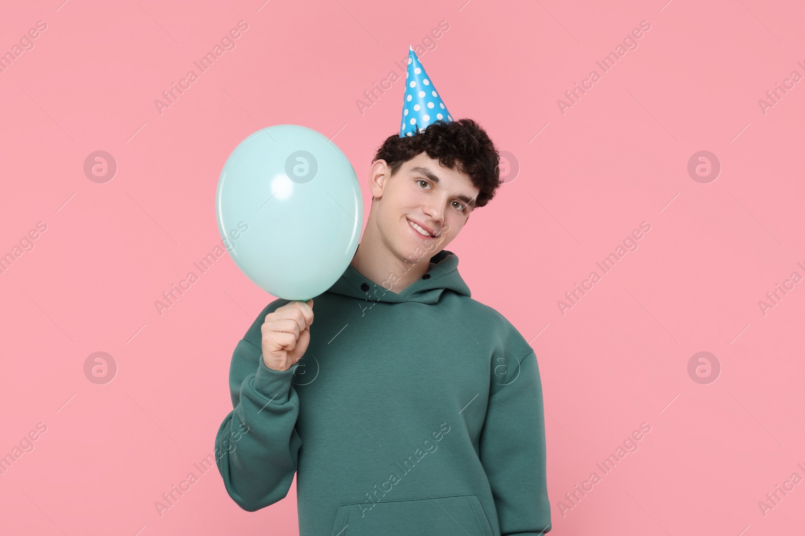 Photo of Young man in party hat with balloon on pink background