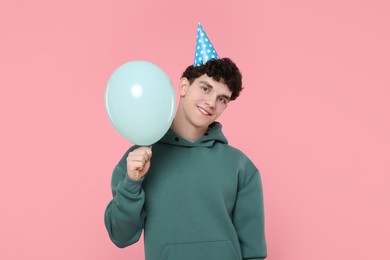 Photo of Young man in party hat with balloon on pink background