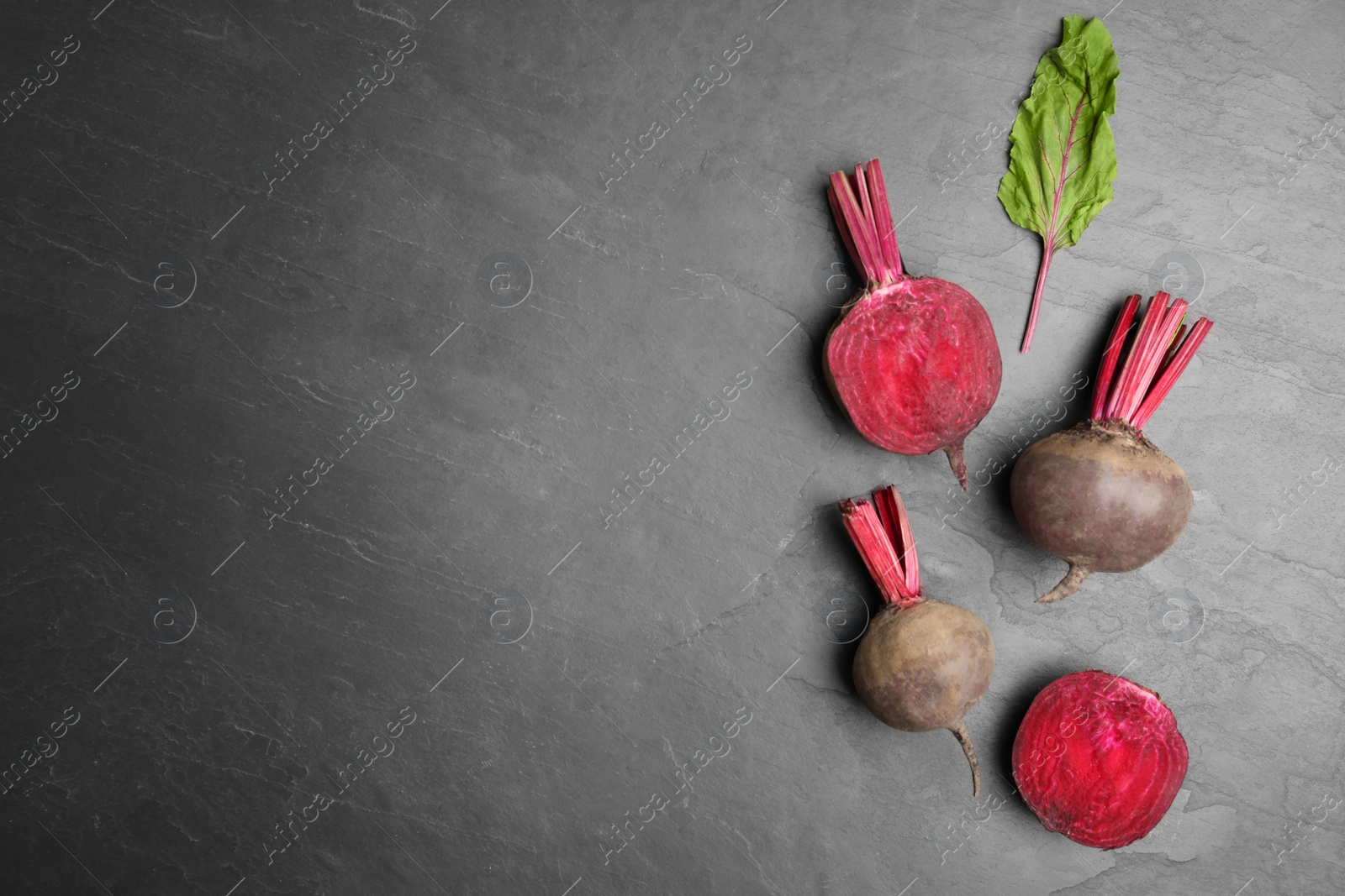 Photo of Cut and whole raw beets on grey table, flat lay. Space for text