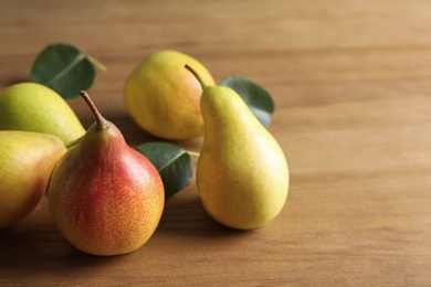 Photo of Ripe pears on wooden table. Space for text