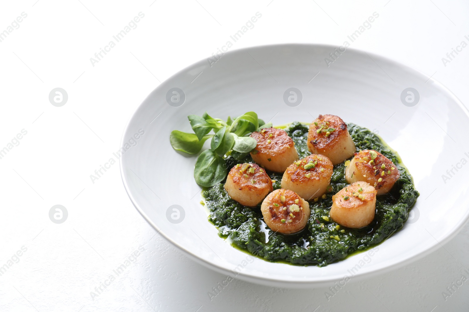 Photo of Delicious fried scallops with tasty sauce and corn salad in bowl on white table, closeup