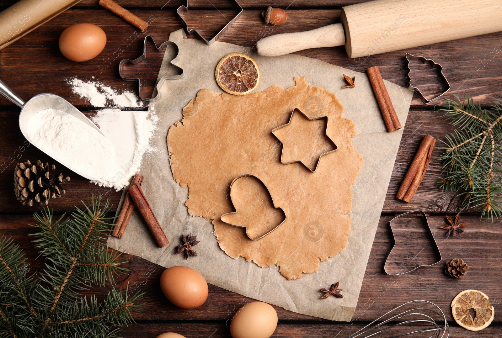 Photo of Dough, different cutters and ingredients for Christmas cookies on wooden table, flat lay