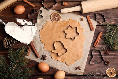 Dough, different cutters and ingredients for Christmas cookies on wooden table, flat lay